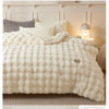 A fluffy white plush winter comforter draped on a bed with light wood and neutral bedding.