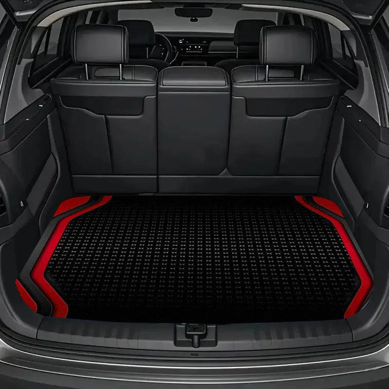 Interior view of a car trunk with black leather seats and a black and red textured floor mat.