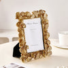 An elegant golden ginkgo leaf resin photo frame displayed on a light surface.