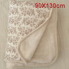 A beige floral muslin baby blanket folded and displayed on a light fabric background.