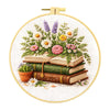A circular embroidery kit featuring floral designs and stacked books on a white background.