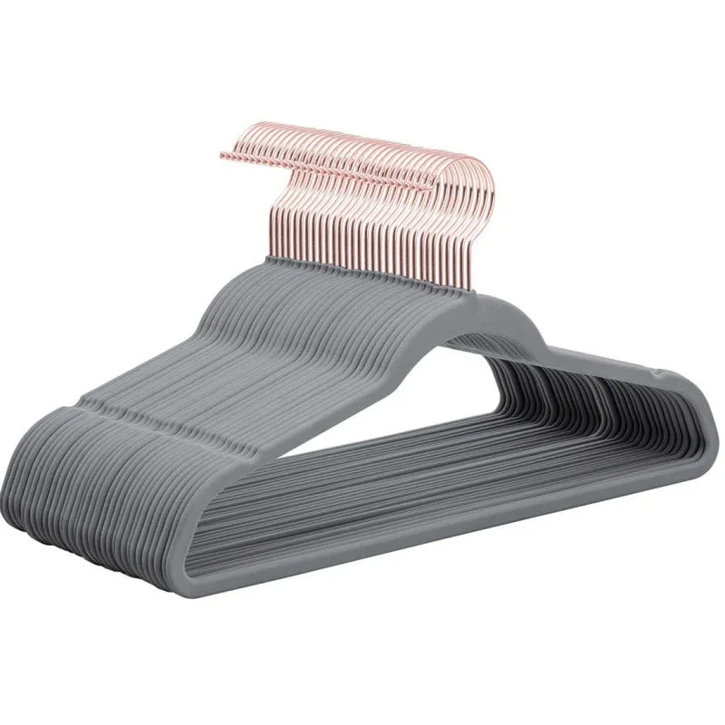 A set of gray velvet hangers with pink 360 degree swivel hooks for clothing.