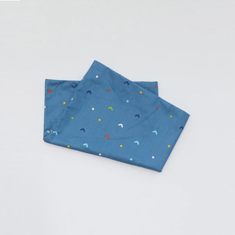 A blue soft cotton baby pillowcase featuring a scattered cartoon design of various colored shapes.