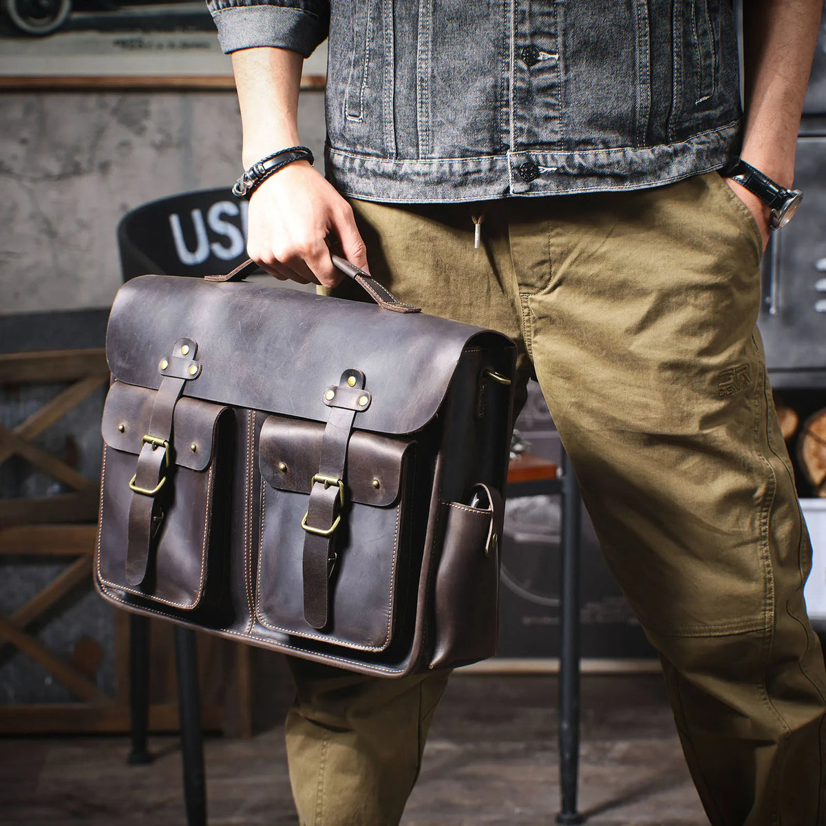 Eine Person hält eine dunkelbraune Vintage-Ledertasche für Laptops.