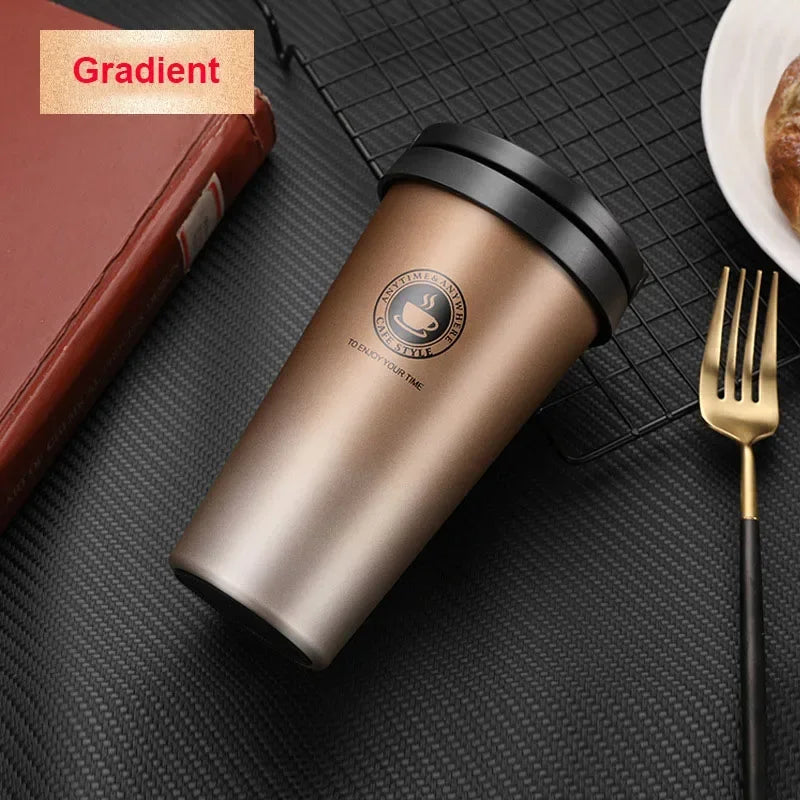 Braune, isolierte Reise-Kaffeetasse mit schwarzem Deckel auf dunkler Oberfläche neben einem Löffel.