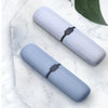 A pair of light blue dust-proof toothbrush travel cases resting on a white marble surface.