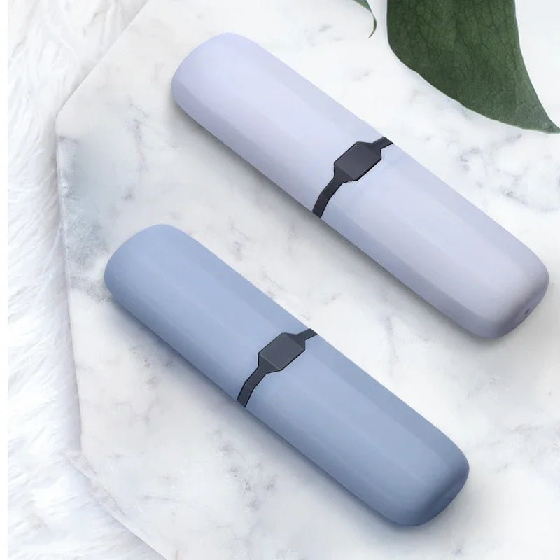 A pair of light blue dust-proof toothbrush travel cases resting on a white marble surface.