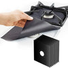 A hand is placing a black reusable stove burner mat into a black stovetop grate.