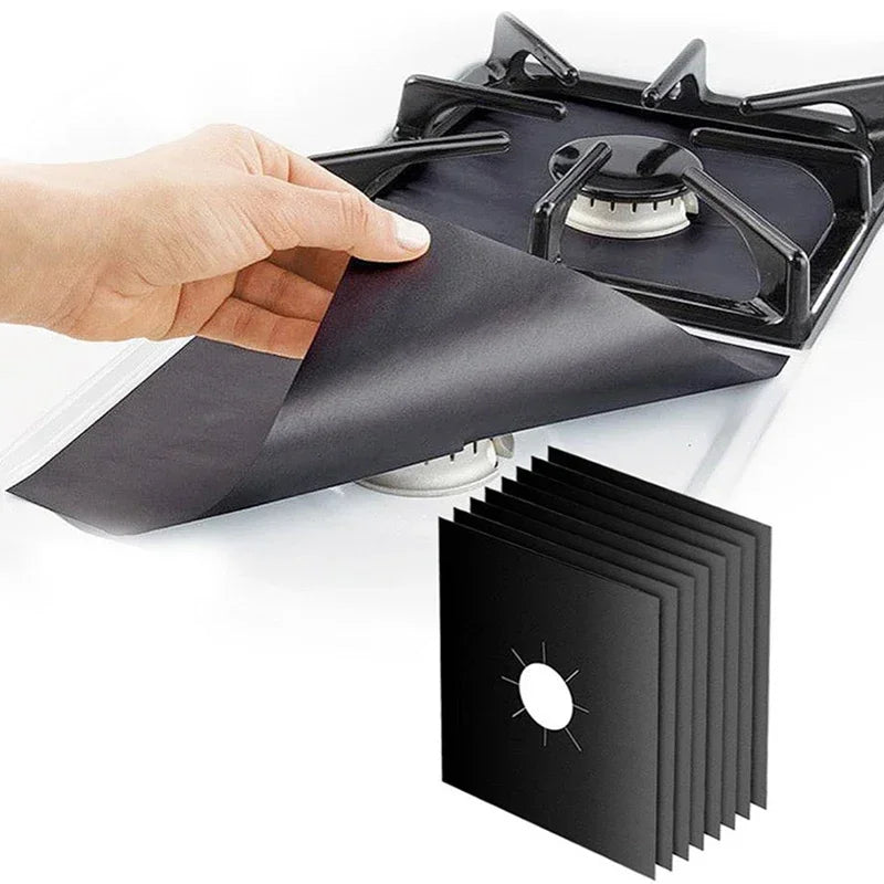A hand is placing a black reusable stove burner mat into a black stovetop grate.