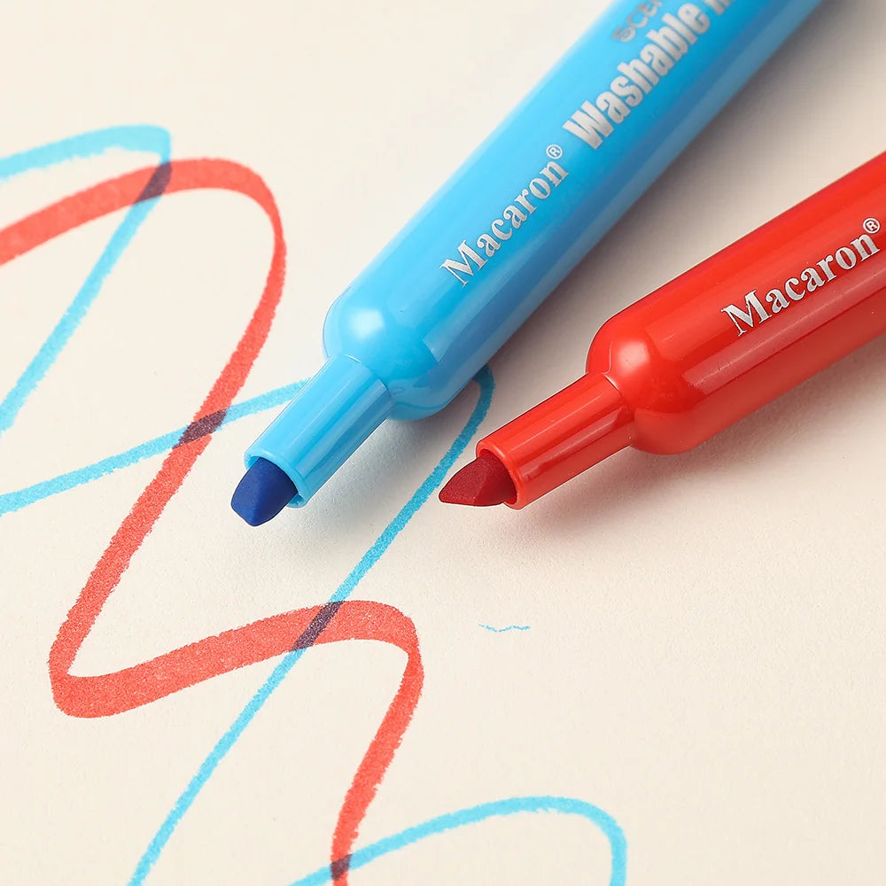 Two Macaron washable markers, one blue and one red, are shown writing on a white sheet of paper.