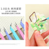 A hand holds a pair of colored craft tweezers used for macaron color work or scrapbooking.