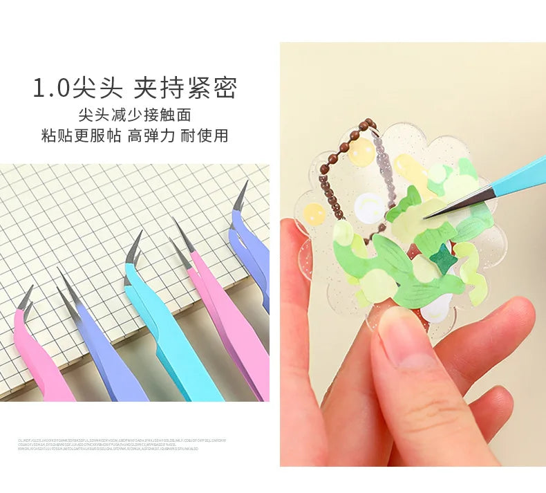 A hand holds a pair of colored craft tweezers used for macaron color work or scrapbooking.