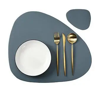 A set of dark gray reversible non-slip placemats with a white plate and silverware on a table.