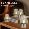A set of flameless candle lights in silver metal holders resting on a book and wooden surface.