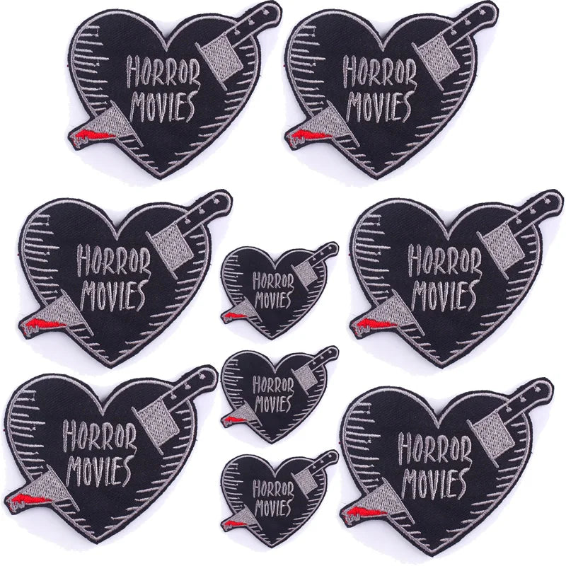 A set of ten black heart-shaped embroidered iron-on patches featuring the text Horror Movies and a stylized hammer design.