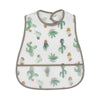 A white baby feeding bib with a brown trim featuring a pattern of green cacti and small pink flowers.