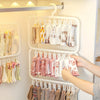 A white laundry drying rack with multiple hanging clips holding various colored fabric items.