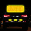 Rear view of a car with bright yellow reflective safety strips illuminated against a dark background.
