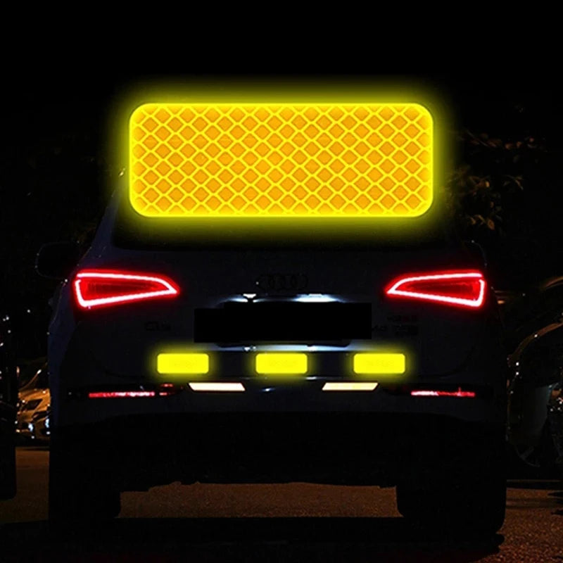 Rear view of a car with bright yellow reflective safety strips illuminated against a dark background.