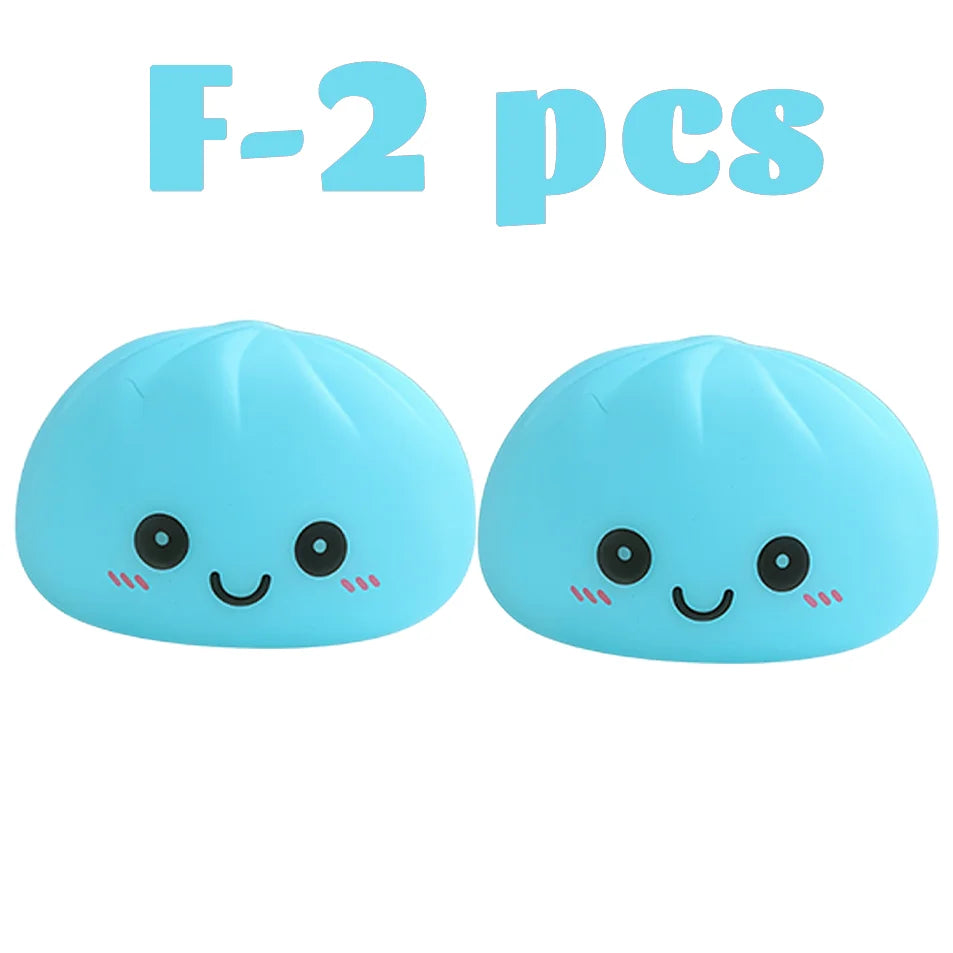 Dos juguetes suaves de color azul claro con forma de dumplings sonrientes.