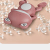 A pink wind-up swimming frog bath toy floating among clear bubbles on a light surface.