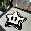 A black and white irregular pentagram rug is displayed on a light surface next to a potted plant and a textured cushion.