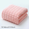 A stack of soft pink coral velvet bath towels shown flat on a white surface.
