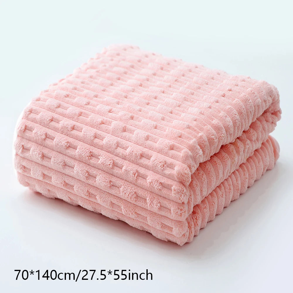 A stack of soft pink coral velvet bath towels shown flat on a white surface.