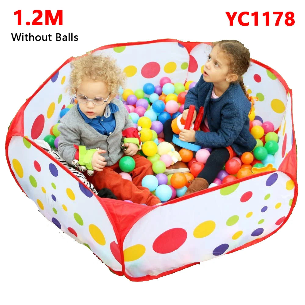 A toddler and a young girl are playing inside a red and multi-colored ball pit play tent.
