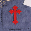 A single vibrant red embroidered cross patch on a dark blue fabric background.