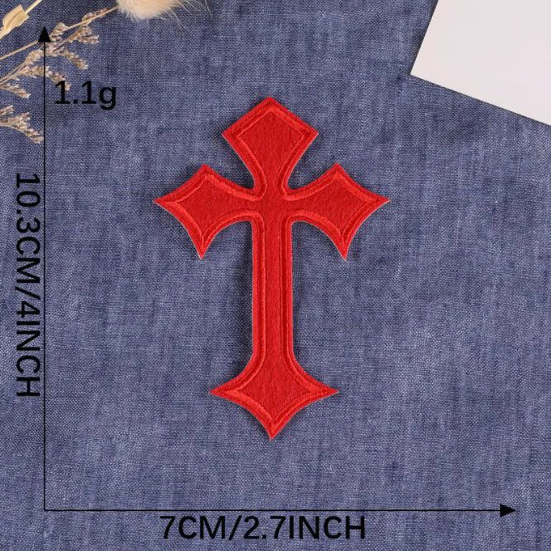 A single vibrant red embroidered cross patch on a dark blue fabric background.
