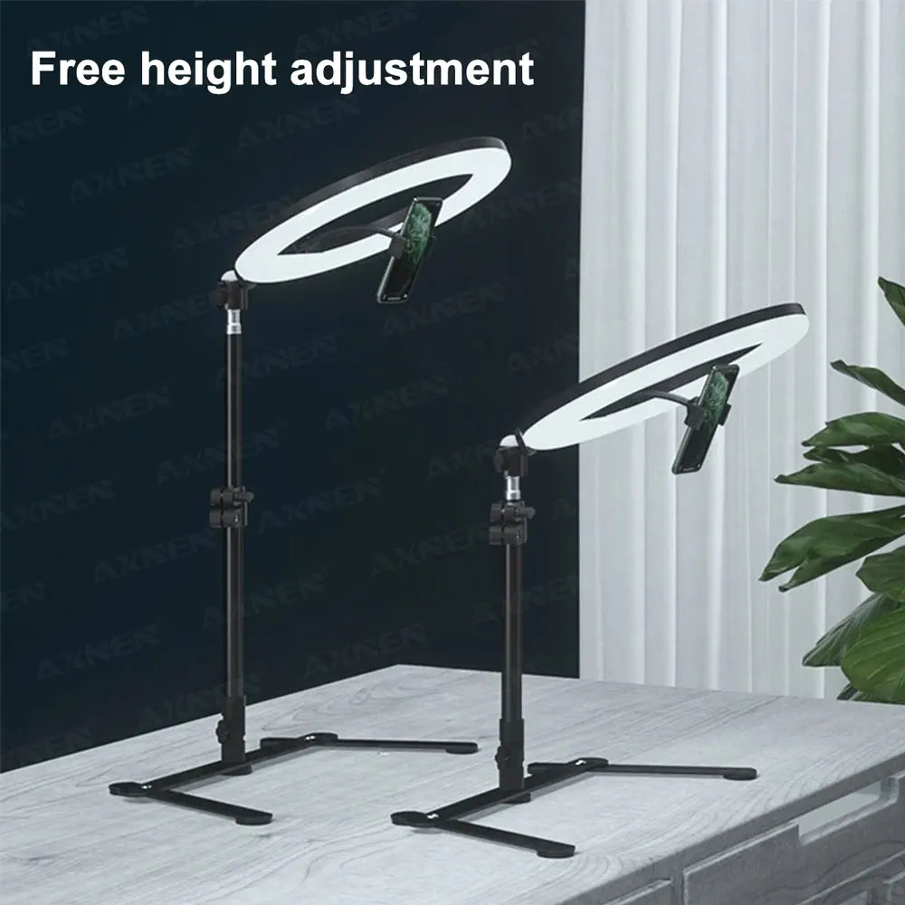 A black foldable overhead tripod with a ring light is shown on a white table.