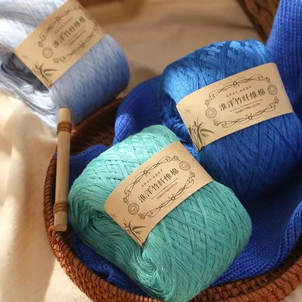 A collection of blue and teal pure cotton yarn balls are displayed in a woven basket.