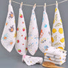 A display of white and yellow patterned muslin baby washcloths hanging on a line with a wooden brush.