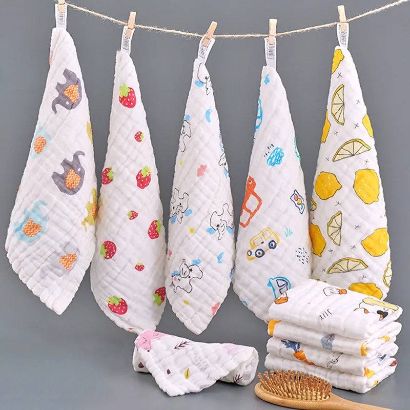 A display of white and yellow patterned muslin baby washcloths hanging on a line with a wooden brush.
