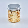 A glass jar filled with metallic gold foil flakes, sealed with a silver lid.