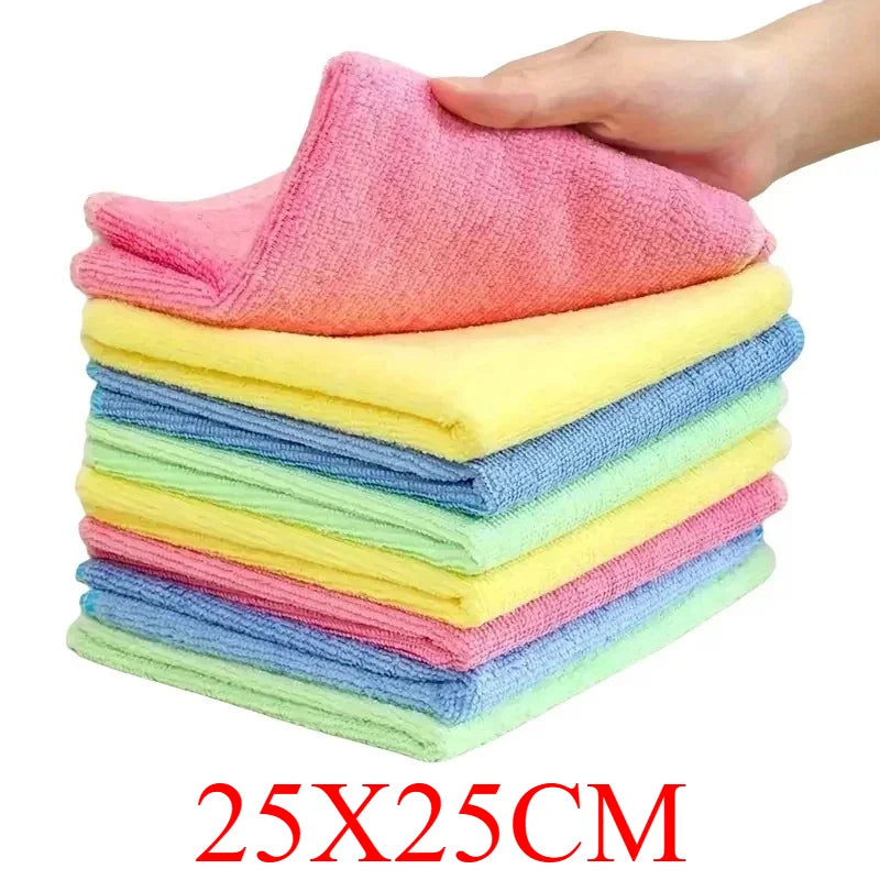 A hand is holding a stack of brightly colored pink, yellow, and blue microfiber cleaning cloths.