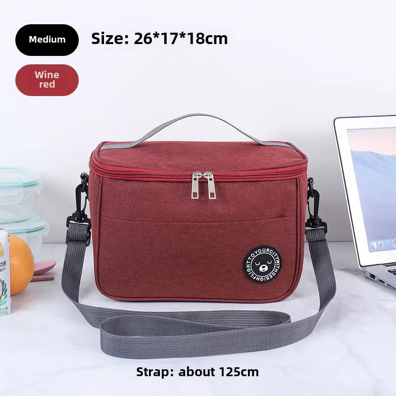 A maroon insulated lunch bag with a gray shoulder strap is shown on a white surface.