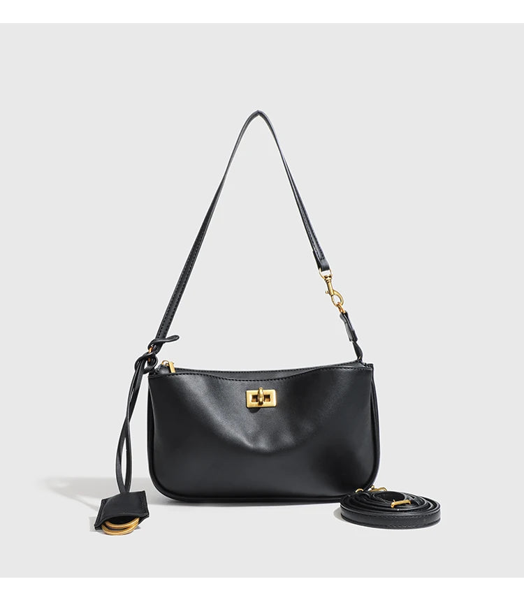 A black leather tote bag with a long strap and a gold-toned metal buckle.