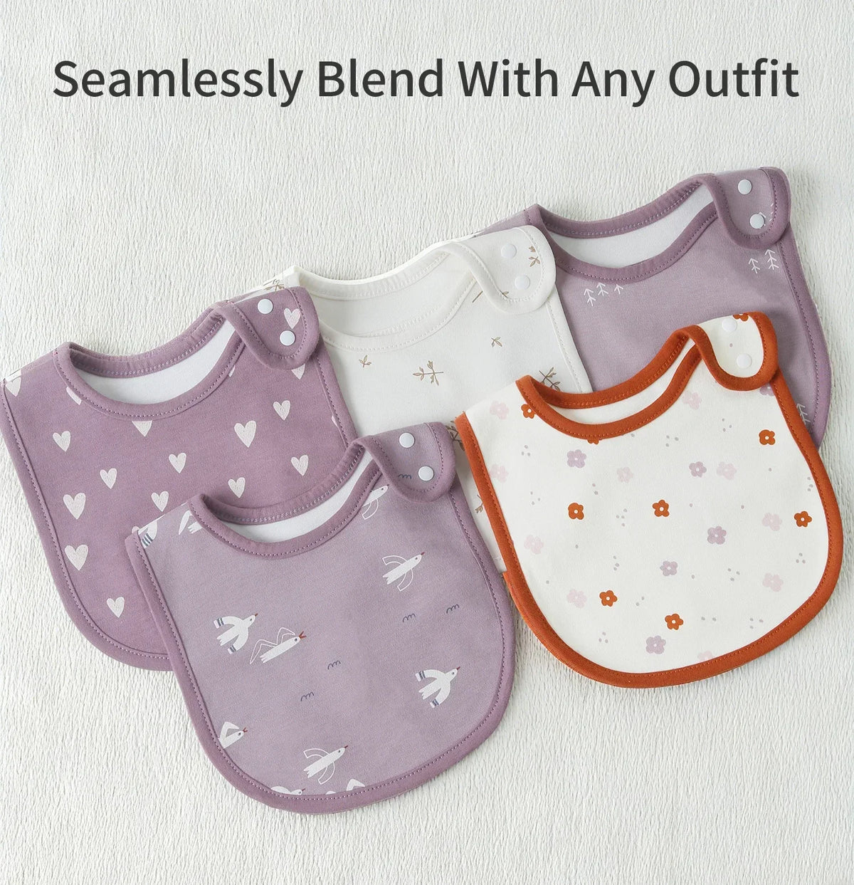 A set of purple and white cotton baby bibs with floral patterns are displayed on a white background.