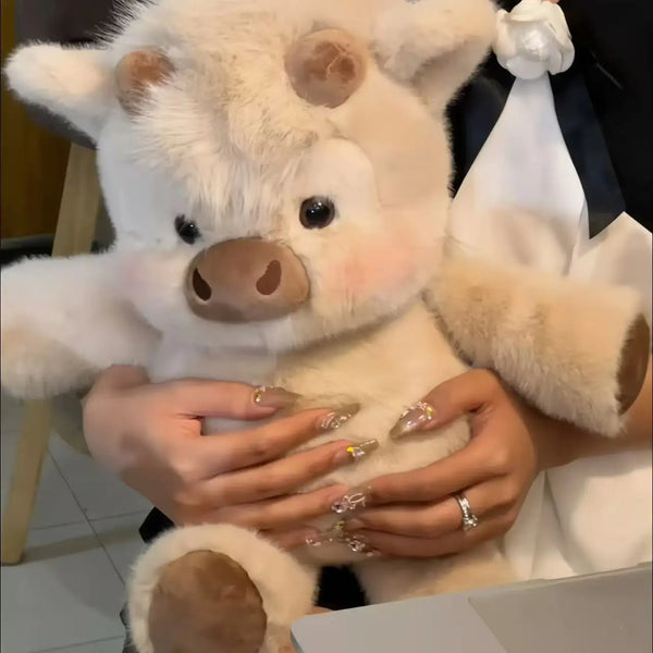 A person is holding a white Highland cattle plush toy.