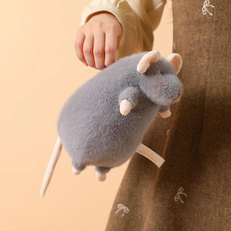 A small gray plush mouse stuffed animal being held by a person, with a white loop attached.
