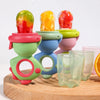 A set of colorful rotating silicone baby fruit feeders with dinosaur designs displayed on a wooden board.