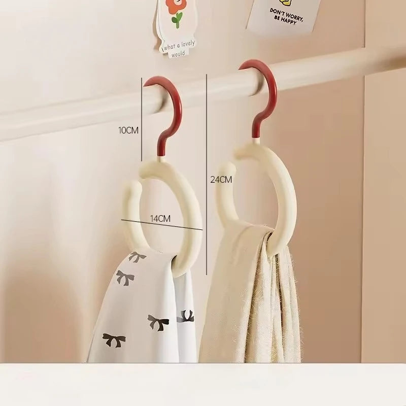 A white wall-mounted organizer hook displaying a folded cream colored scarf and hat.
