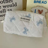 A white quilted cosmetic bag with blue bow print and the jolly house label.