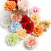 A collection of lifelike silk peony flower heads in various shades of peach, pink, orange, and yellow.