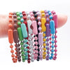 A collection of colorful ball bead chains in various shades of pink, purple, green, and blue are displayed on a hand.