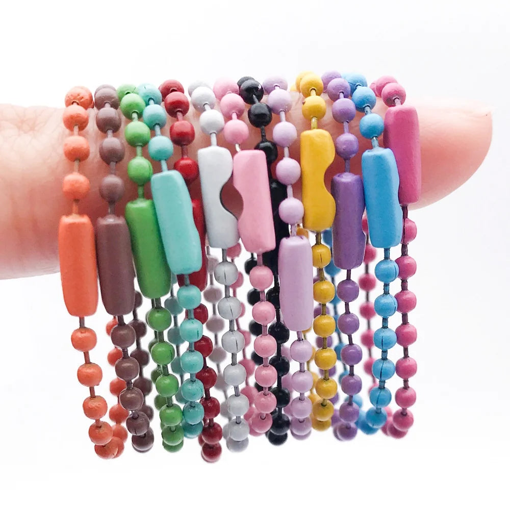 A collection of colorful ball bead chains in various shades of pink, purple, green, and blue are displayed on a hand.
