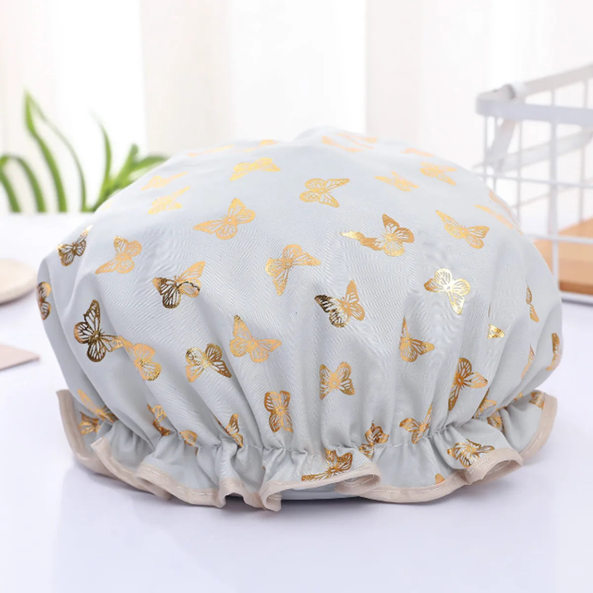 Light blue reusable elastic shower cap decorated with gold butterfly patterns