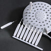 A white shower cleaning brush set with multiple nozzles and a handle is shown on a dark surface.